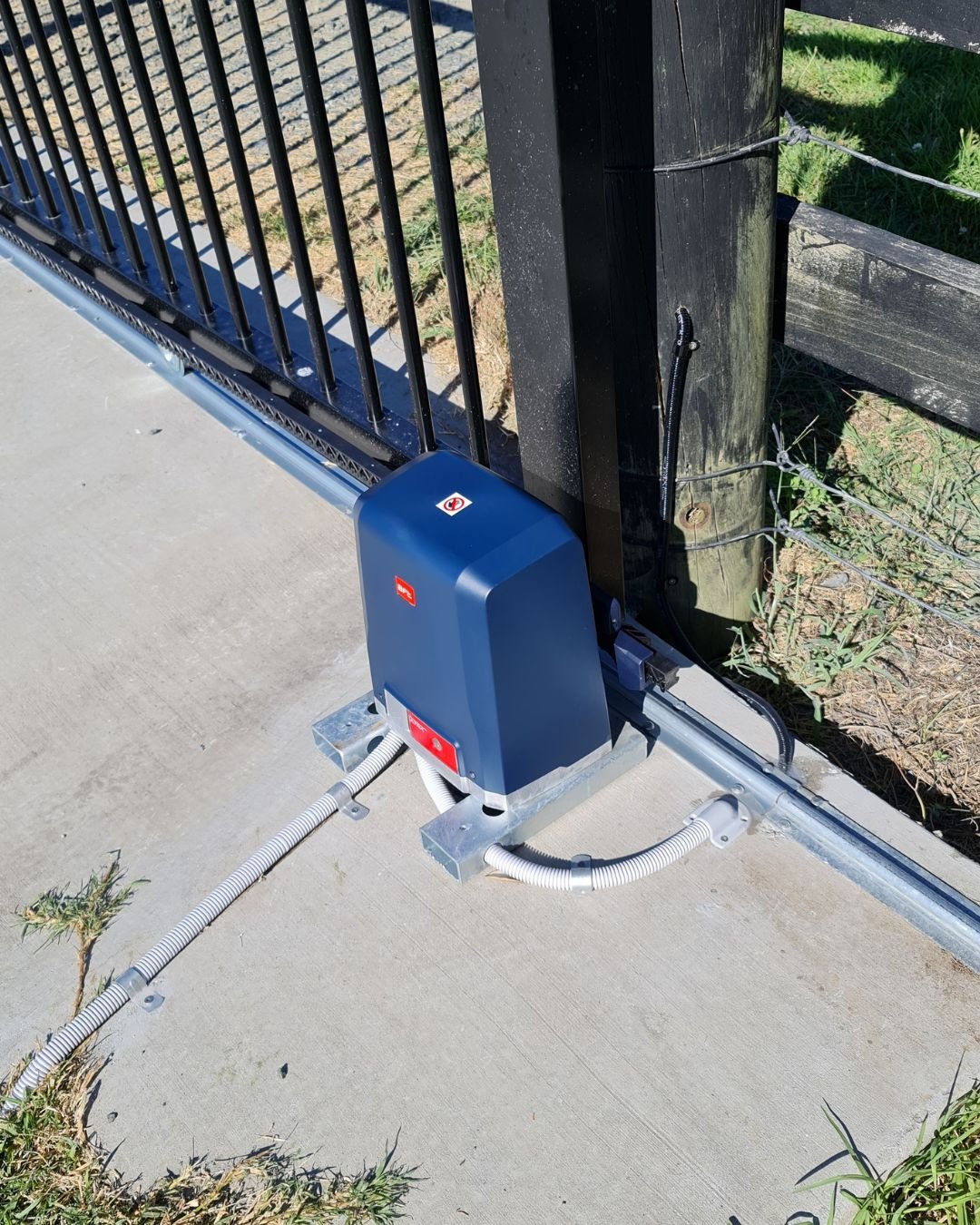 Gate opener arm installed at the base of a driveway gate on a new concrete driveway in Dairy Flat, Auckland