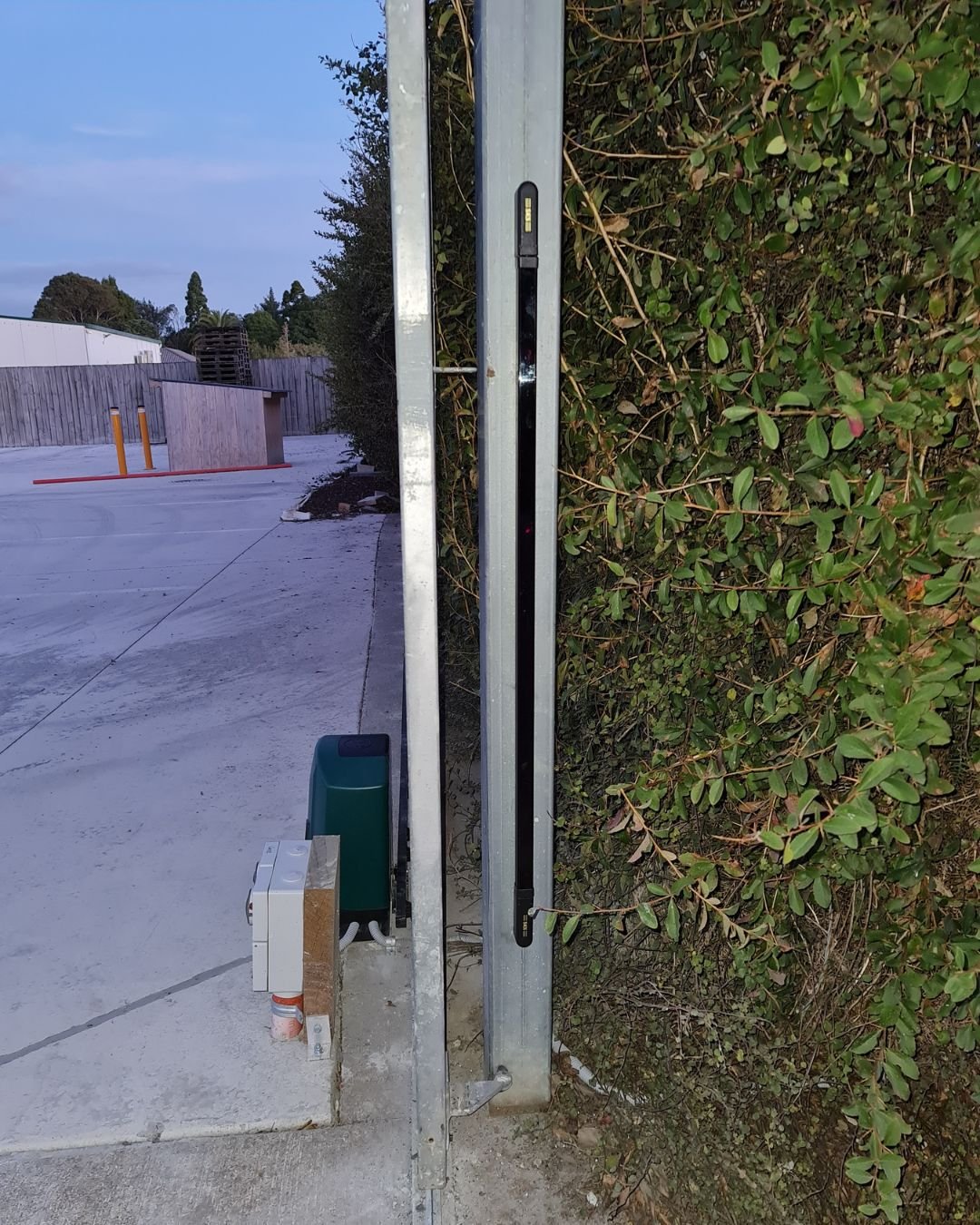 Photoelectric safety beams mounted at two heights on a barrier arm post at a commercial truck entrance in Rosedale, Auckland
