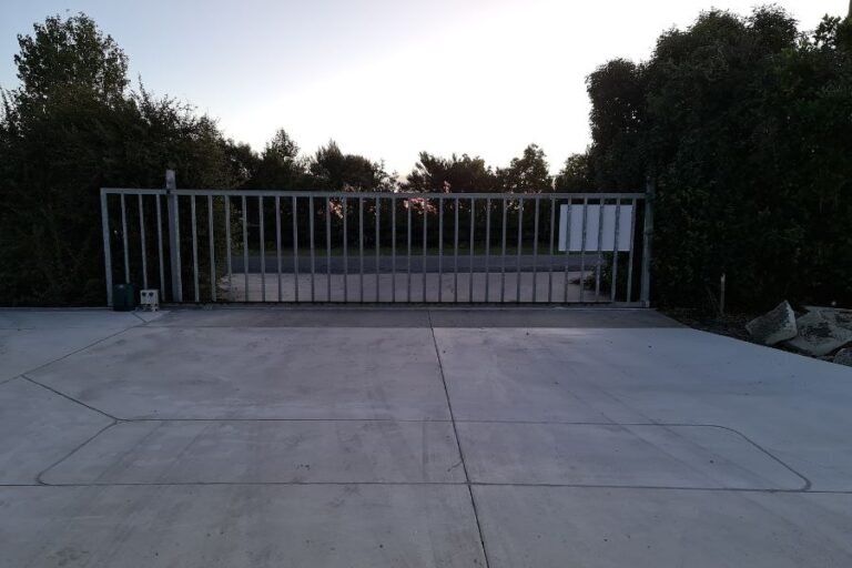Large automatic sliding gate standing open across a wide concrete entrance at a commercial property in Warkworth, Rodney